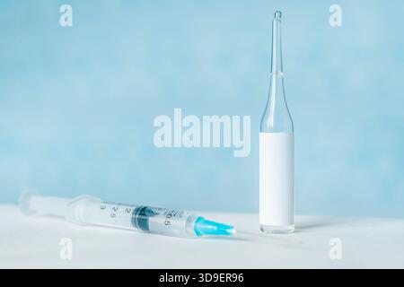 flacons ou flacons de vaccins médicaux et une seringue sur fond bleu. modèle de flacon vierge pour étiquette. étiquette blanche vide sur le flacon pour texte Banque D'Images