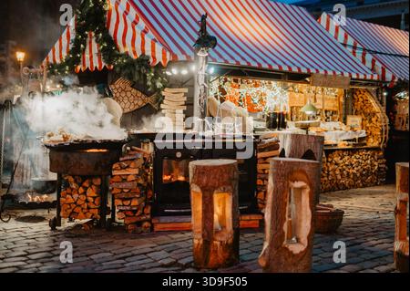 Stand de nourriture et grill au bois de chauffage au marché de Noël de Riga à Doma Laukums Banque D'Images