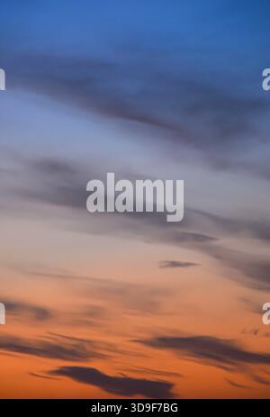 Un coucher de soleil éclatant transforme le ciel avec des couleurs éclatantes, mettant en évidence les nuages doux dans une scène apaisante de fin d'après-midi pleine d'atmosphère. Banque D'Images