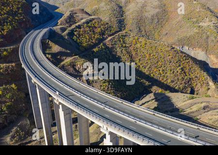 Vue surélevée par drone du viaduc de l'autoroute A1 traversant le terrain escarpé et accidenté de Kolsh dans le comté de Kukës, entouré de collines aux couleurs d'automne et du dr. Banque D'Images