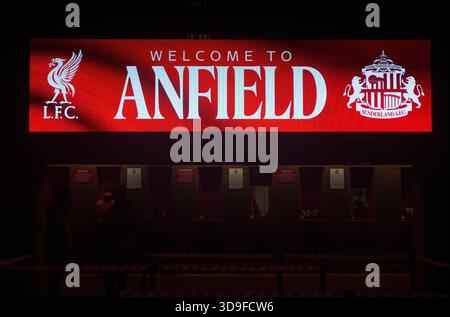 Vue nocturne de la billetterie du stade Anfield, avec un panneau lumineux lumineux « Welcome to Anfield » au-dessus des guichets de service et de la silhouette du personnel Banque D'Images