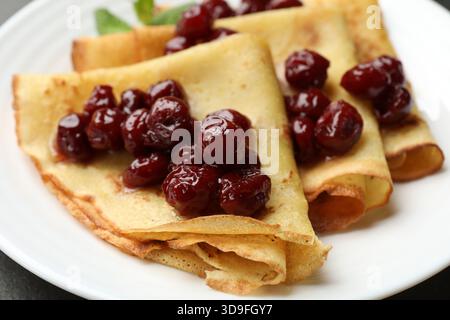 Crêpes savoureuses aux cerises et à la menthe sur la table, gros plan Banque D'Images
