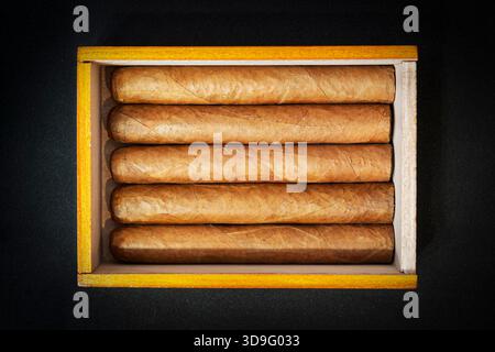 Boîte de cigares cubains sur une table noire dans le noir. Cigares chers en cadeau. Banque D'Images