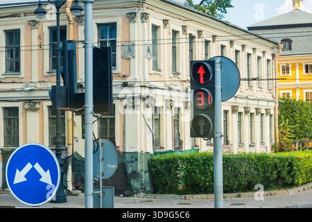 Scène de rue représentant une intersection urbaine avec un feu rouge avec un compte à rebours, un panneau routier bleu et une façade de bâtiment rénovée U. Banque D'Images