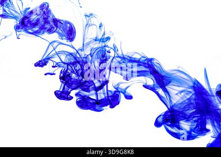 Encre bleue injectée dans l'eau à partir de la seringue, mélange de couleurs avec de l'eau créant des formes abstraites Banque D'Images