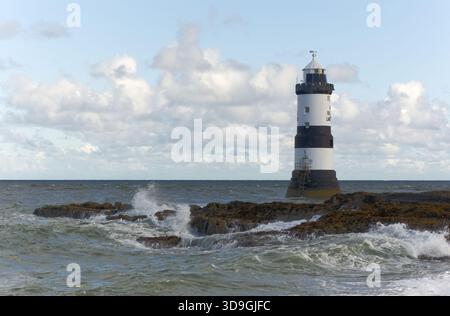 Les vagues se brisent contre la rive rocheuse à la base du phare de Trwyn du, également connu sous le nom de phare de Penmon, à Penmon point sur la côte est d'an Banque D'Images
