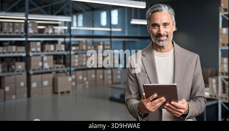 Gestionnaire d'entrepôt tenant la tablette debout près du fond des boîtes en carton. Banque D'Images