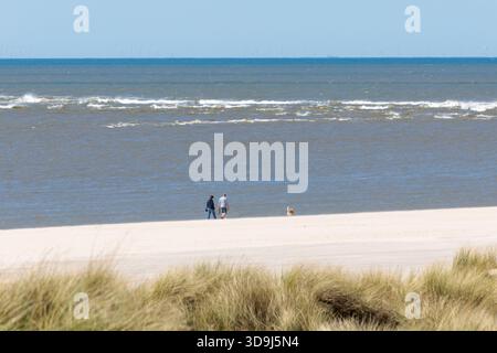 Couple promenant leur chien le long de la côte danoise Banque D'Images