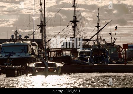 Un yacht club au coucher du soleil, des yachts et des voiliers sont amarrés aux couchettes, d'énormes défenses accrochées à des méga yachts, des cordes épaisses, des reflets sur les côtés brillants Banque D'Images