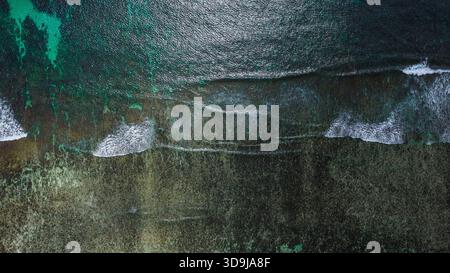 Structure de corail submergée avec des vagues brisantes et une surface océanique chatoyante Banque D'Images