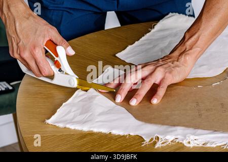 Femme coupant le tissu en utilisant le motif pour la conception de la mode Banque D'Images