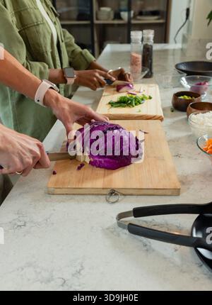 Chou violet tranché sur une planche de bois sur un comptoir en marbre, avec des pots à épices, des bols de riz Banque D'Images