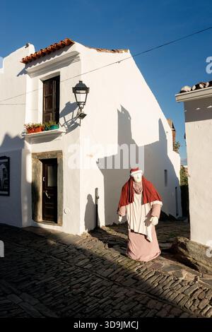 Monsaraz, Portugal - 07 décembre 2024 : figure de la nativité en plein air sur la rue principale de Monsaraz, Portugal, ensoleillée et encadrée par une étroite ruelle latérale. Banque D'Images