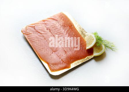 Saumon ​​smoked finement tranché, garni de quartiers de citron et d'aneth frais isolé sur fond blanc. Fruits de mer. Vue de dessus. Banque D'Images