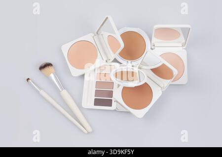 Produits cosmétiques de maquillage et de beauté, poudres compactes ouvertes et palette de fards à paupières avec des pinceaux doux. Isolé sur une surface blanche. Publicité pour STO Banque D'Images