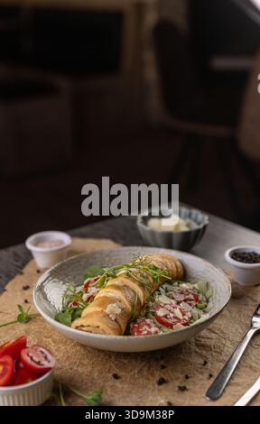 Roulé aux œufs avec fromage dans une assiette servi avec des tomates sur la table Banque D'Images