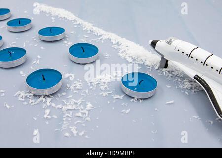 Navette spatiale jouet avec bougies bleues et neige décorative formant scène créative de vacances d'hiver Banque D'Images