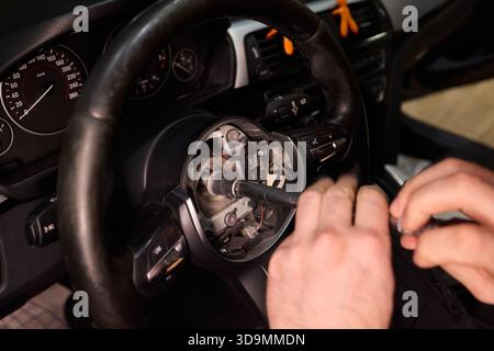 Réparation détaillée de la voiture, prise de vue ciblée des mains restaurant soigneusement le composant de direction du véhicule, travail de précision sur le volant du véhicule avec des outils dans Banque D'Images