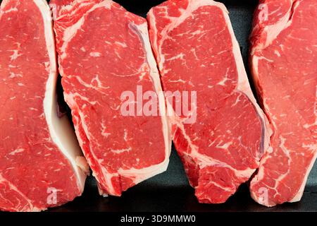 Vue aérienne vue rapprochée d'un steak New-yorkais dans un plateau de vente au détail de boucher en mousse noire. Banque D'Images