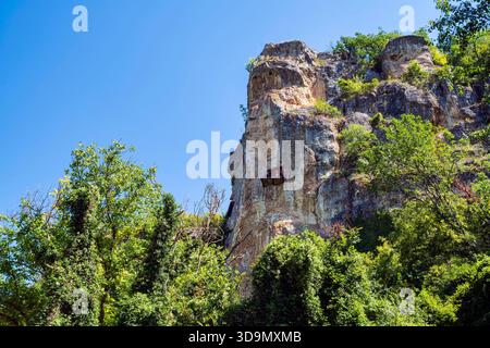 Une falaise de calcaire spectaculaire dans la zone des églises taillées dans le rocher d'Ivanovo, avec un petit balcon en bois construit dans la paroi rocheuse au-dessus de la forêt verte dense Banque D'Images