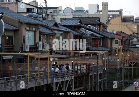 Les terrasses de restauration « kawayuka » (川床) situées en bordure de rivière offrent une brise fraîche naturelle dans les chaudes soirées estivales le long de la rivière Kamo à Kyoto, au Japon. Banque D'Images