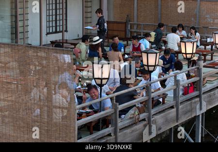 Les terrasses de restauration « kawayuka » (川床) situées en bordure de rivière offrent une brise fraîche naturelle dans les chaudes soirées estivales le long de la rivière Kamo à Kyoto, au Japon. Banque D'Images