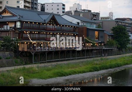 Les terrasses de restauration « kawayuka » (川床) situées en bordure de rivière offrent une brise fraîche naturelle dans les chaudes soirées estivales le long de la rivière Kamo à Kyoto, au Japon. Banque D'Images