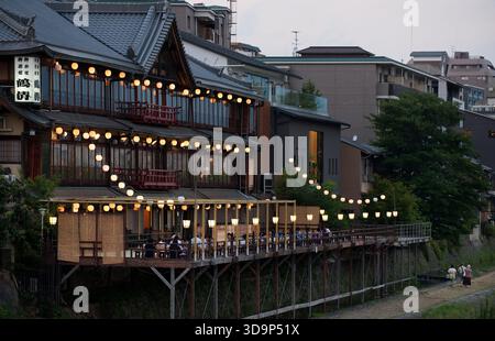 Les terrasses de restauration « kawayuka » (川床) situées en bordure de rivière offrent une brise fraîche naturelle dans les chaudes soirées estivales le long de la rivière Kamo à Kyoto, au Japon. Banque D'Images