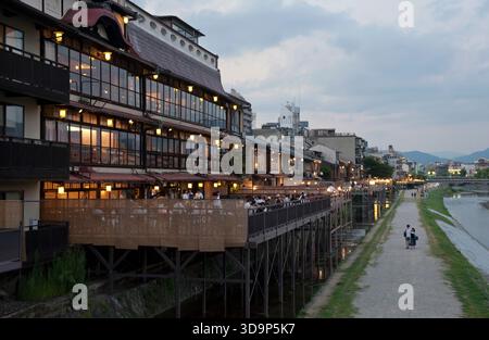 Les terrasses de restauration « kawayuka » (川床) situées en bordure de rivière offrent une brise fraîche naturelle dans les chaudes soirées estivales le long de la rivière Kamo à Kyoto, au Japon. Banque D'Images