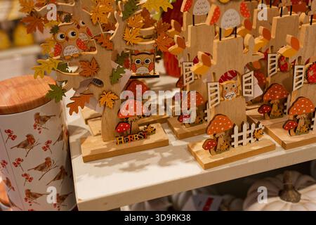 Diverses décorations d'automne en bois sur une table blanche présentent des hiboux sur les arbres avec des champignons de feuilles d'érable et de chêne de petites clôtures et le mot Herbst créant Banque D'Images
