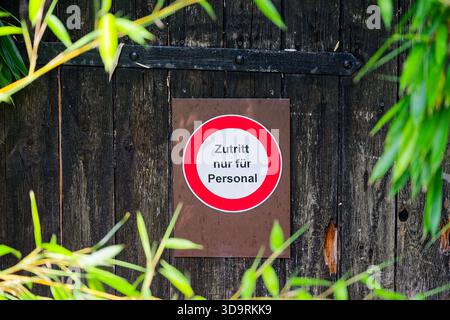 Une vieille porte en bois avec des garnitures en métal noir affiche un signe de cercle rouge marqué en allemand comme le personnel restreignant seulement l'entrée au-delà de la clôture dans une priva Banque D'Images