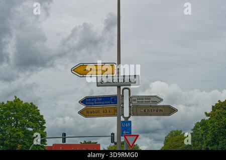 Un grand poteau métallique à flensburg montre de nombreux panneaux de direction. Les flèches vers la droite pointent vers Zentrum et U69 et deux écoles. Panneaux à gauche pour Denmark Hamburg Kiel c Banque D'Images