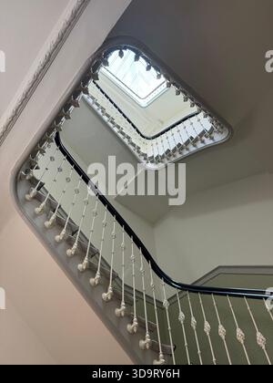 Une vue d'un escalier en colimaçon d'en bas, mettant en valeur des garde-corps complexes et un plafond miroir reflétant les courbes de l'escalier. Banque D'Images