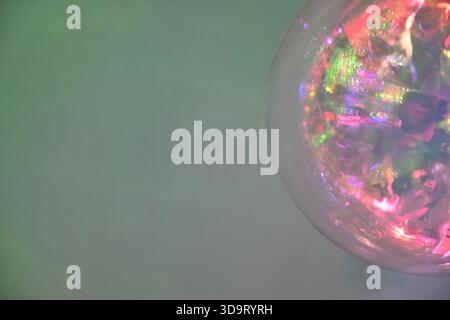 Gros plan d'un orbe coloré et réfléchissant avec un arrière-plan doux et flou. L'orbe affiche un mélange de couleurs éclatantes et de reflets lumineux, créant un dr. Banque D'Images