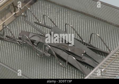 Vue rapprochée des instruments chirurgicaux disposés soigneusement dans un bac de stérilisation. Les instruments sont métalliques et brillants, mettant en valeur leur desi précis Banque D'Images