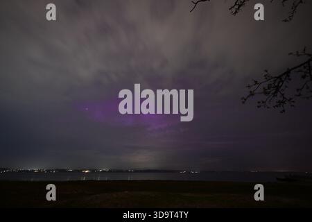 Un ciel nocturne serein au-dessus d'un plan d'eau calme à Solituede Flensburg allemagne, avec un soupçon de lumière violette au milieu des nuages. La scène est illumina Banque D'Images