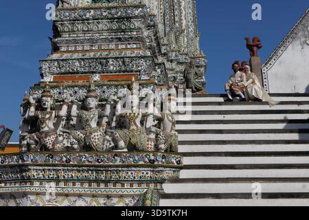 UN JEUNE COUPLE MARIÉ ASSIS SUR LES MARCHES DU WAT ARUN. TEMPLE BOUDDHISTE Banque D'Images