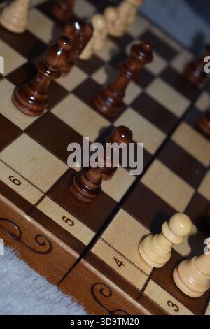 Pièces d'échecs noires et blanches sur un échiquier en bois Banque D'Images