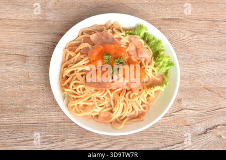 Spaghettis sautés épicés avec sauce jambon porc en tranches de sauce rose coréenne nappant œuf de crevettes sur assiette Banque D'Images