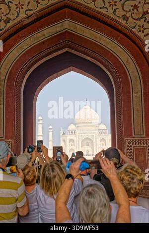Une tour en dôme du Fort Rouge d'Agra vue à travers une arche ornée à l'heure dorée, avec un oiseau perché sur le pinacle dans la lumière chaude du soir. Banque D'Images