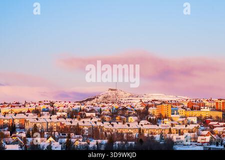Kiruna skyline, Suède, en hiver avec des teintes orange et rouge du soleil bas. Neige. Maisons colorées. Pistes de ski. Banque D'Images