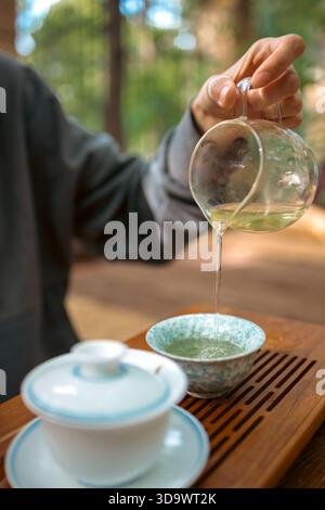 Un moment de verser du thé chaud dans un cadre traditionnel. Le flux concentré de thé fraîchement infusé relie la théière et la tasse, symbolisant le rituel Banque D'Images