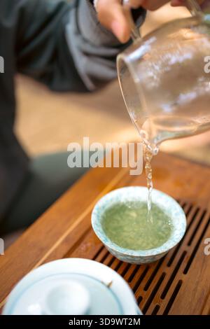 Un moment de verser du thé chaud dans un cadre traditionnel. Le flux concentré de thé fraîchement infusé relie la théière et la tasse, symbolisant le rituel Banque D'Images