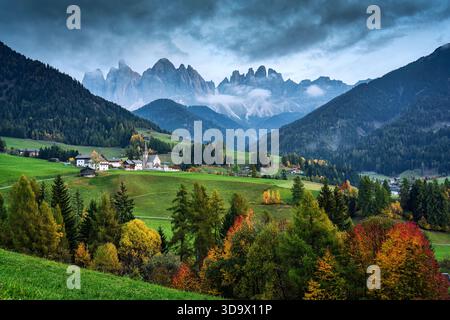 Vue pittoresque du village de Santa Maddalena avec église Magdalena entourée par la forêt d'automne et brumeuse chaîne de montagnes Odle dans Val di Funes, Dolom Banque D'Images