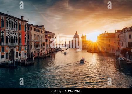 Belle vue du lever du soleil sur le Grand canal avec bateau crusing, Santa Maria della Salute, bâtiment classique à Venise, Italie Banque D'Images