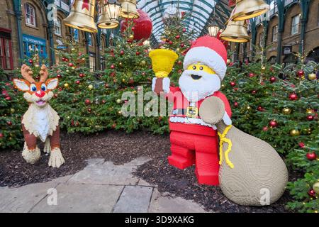 Une exposition en briques Lego représentant le Père Noël et Rodolphe le renne attire l'intérêt des visiteurs sur la place Covent Garden de Londres pendant la période de Noël. Banque D'Images