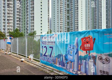 Hong Kong, Chine. 07 décembre 2025. Un garçon pêche à côté d'une affiche pour les élections législatives à Tin Shui Wai. Les élections générales du Conseil législatif de Hong Kong de 2025 ont lieu le 7 décembre 2025 pour élire les 90 membres du 8ème Conseil législatif de Hong Kong. Crédit : SOPA images Limited/Alamy Live News Banque D'Images
