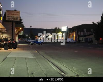 West Yellowstone, Montana, États-Unis - 23 septembre 2025 : une vue donnant sur une rue principale bordée de boutiques, d'hôtels et de panneaux de néon au crépuscule. Banque D'Images
