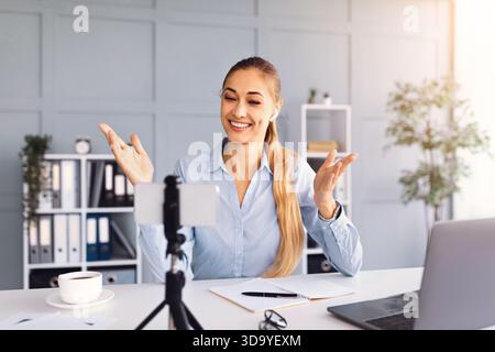 Femme participant à des appels vidéo tout en travaillant à domicile dans un environnement de bureau moderne Banque D'Images