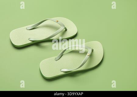 Tongs élégantes féminines sur fond vert Banque D'Images